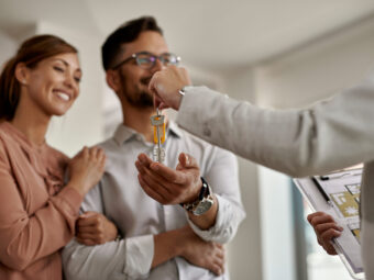 Close-up of real estate agent giving new house keys to a couple.
